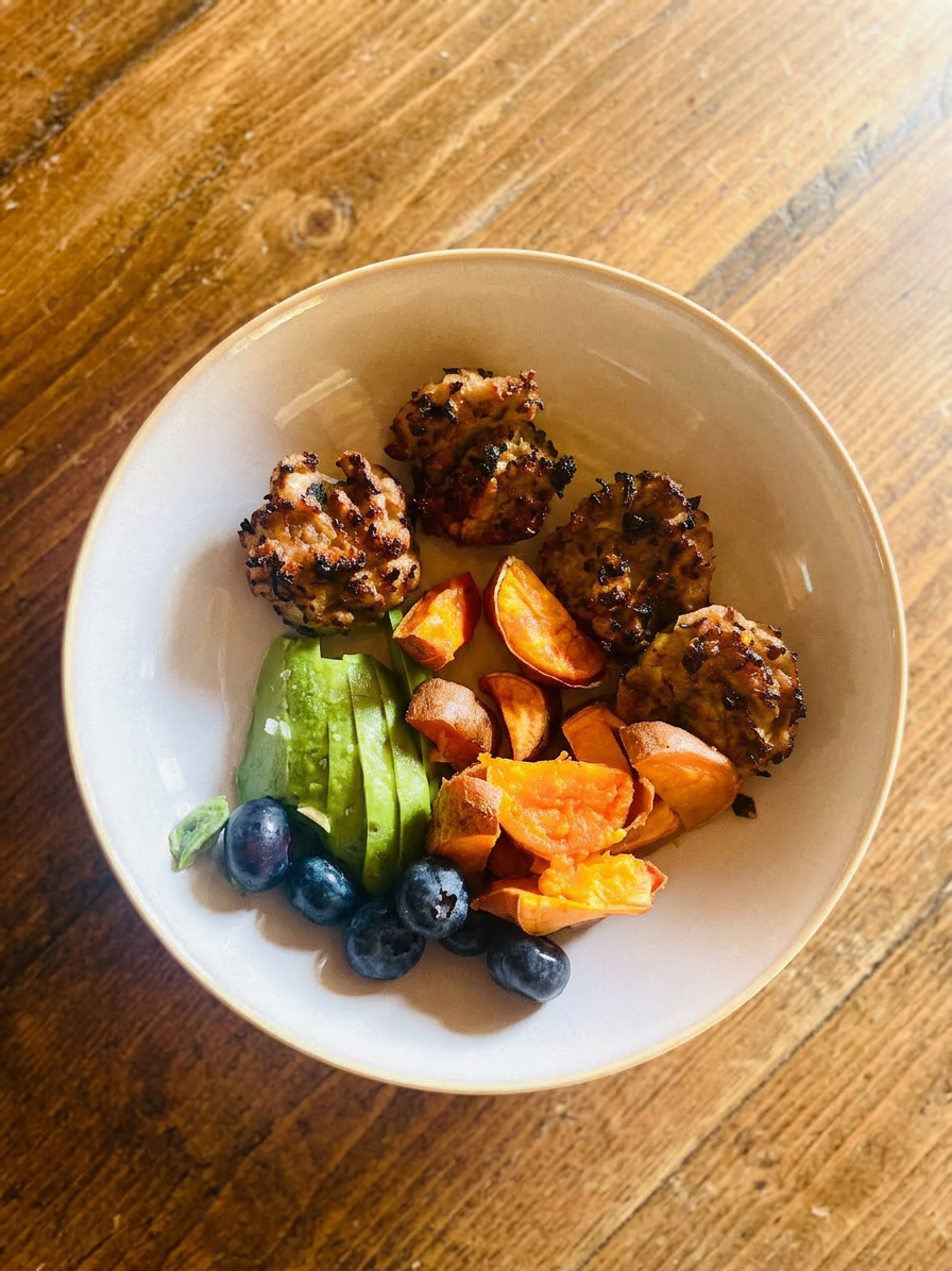 Maple chicken sausage patties in a bowl with avocado, sweet potato and blueberries