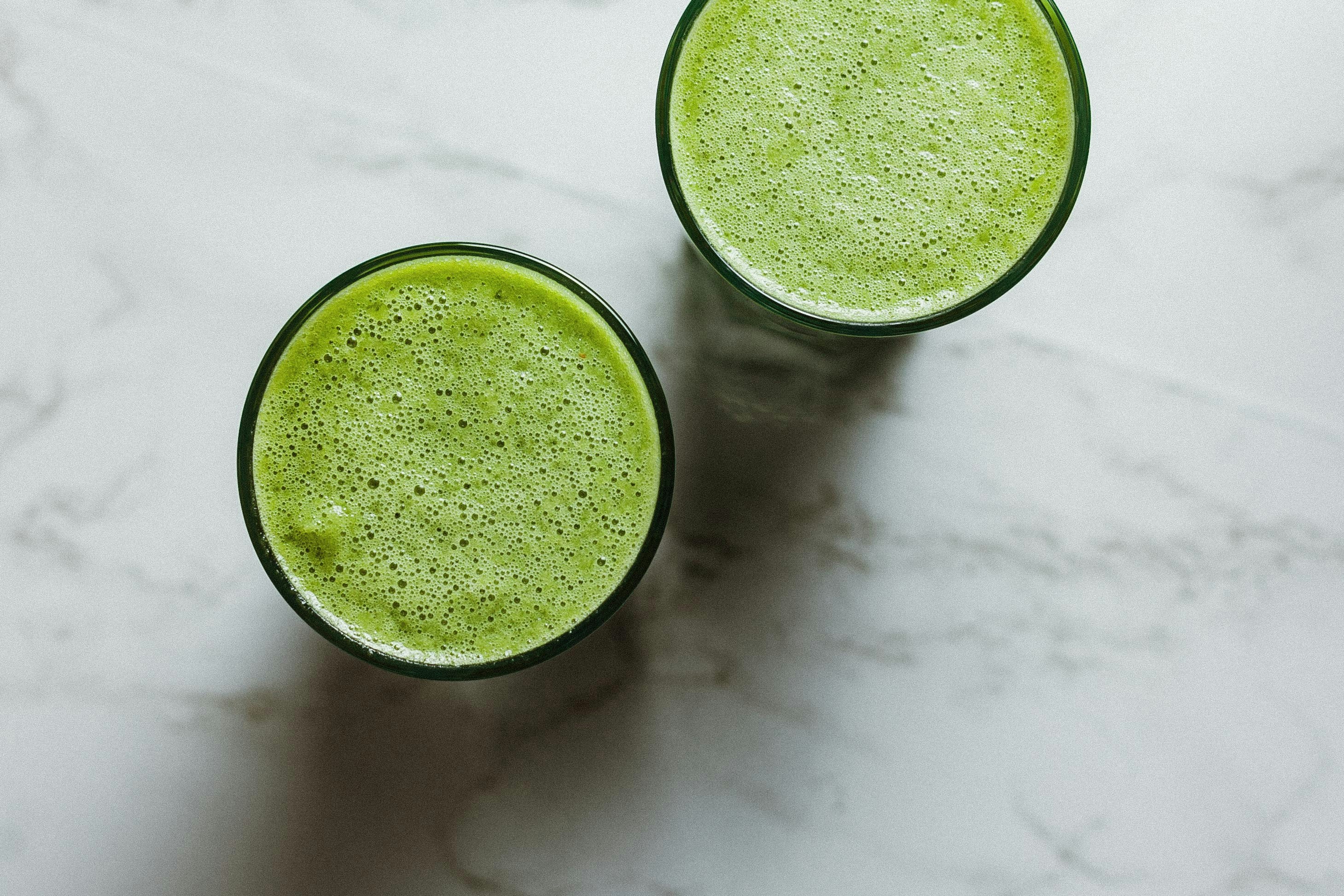 Two glasses of vibrant green AIP smoothie on marble